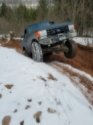 Blue SUV with lifted suspension driving through snow and mud