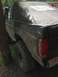 1989 Ford Bronco - This SUV, likely from the 1980s, is covered in mud and has a soft top and large tires.