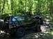 1989 Ford Bronco - Several off-road vehicles navigate a wooded trail, with a black Ford Bronco prominently featured.
