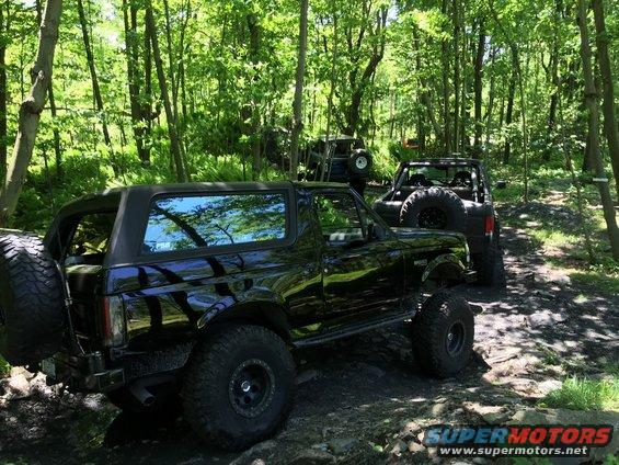 Black 1989 Ford Bronco with lifted suspension on a wooded trail