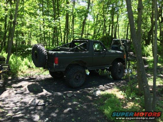 1989 Ford Bronco modified for off-roading, spare tire mounted on rear carrier, in wooded area