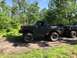 1989 Ford Bronco - A modified dark gray Ford Bronco is parked on a dirt path, with another truck visible behind it.