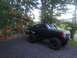 1989 Ford Bronco - Modified 1989 Ford Bronco sits parked on a gravel driveway near a cabin in a wooded area.