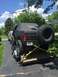 1989 Ford Bronco - A lifted black Bronco with a soft top and large spare tire is secured to a trailer, with another vehicle visible behind it.