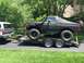 1989 Ford Bronco - A black Ford Bronco is transported on a trailer behind a silver pickup truck.