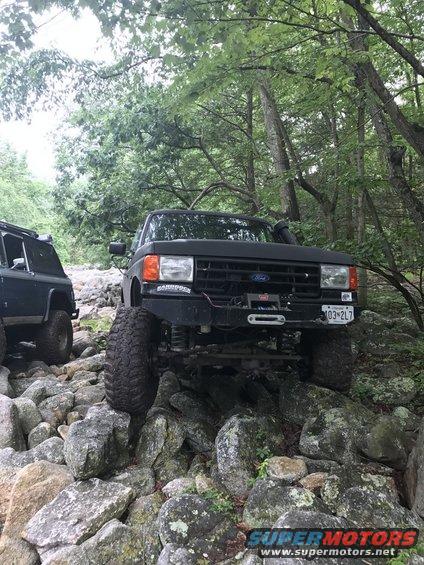 Black 1989 Ford Bronco navigating rocky terrain with another SUV behind