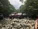 1989 Ford Bronco - Multiple off-road vehicles are seen navigating a challenging rocky path surrounded by trees.