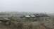 1989 Ford Bronco - A large group of off-road vehicles are gathered on a rocky, uneven surface, obscured by thick fog.