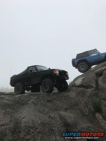 Black Bronco and blue Bronco climbing rocks. Black one is in foreground