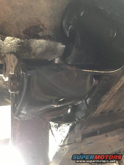 Close-up of a black painted leaf spring shackle bracket, likely from a truck or SUV