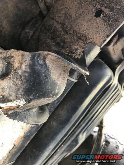 Undercarriage view of a rusty suspension component with a zip tie