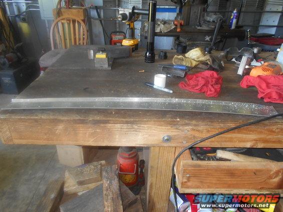Workbench with metal strip, drill, flashlight, and red rags