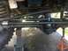1989 Ford Bronco - Close-up view of the steering and suspension system of a 1989 Ford Bronco, elevated on jacks for service.