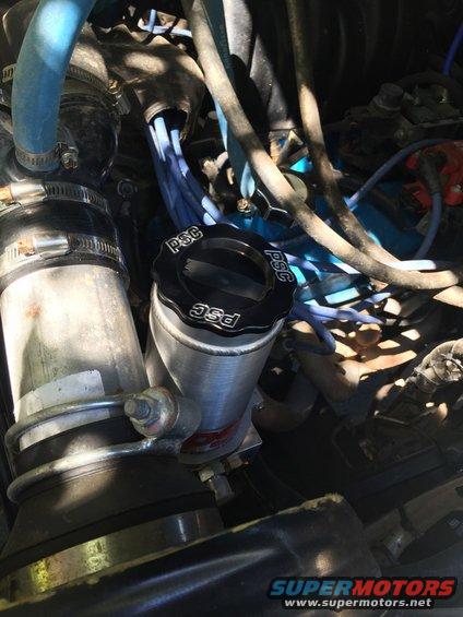 Engine bay with a silver PSC reservoir and black cap, surrounded by hoses and wires
