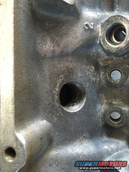 Close-up of a cast iron engine block with bolt holes and a number '2' cast into it