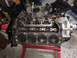 1989 Ford Bronco - Engine block with pistons visible, supported by a red stand. Other engine components are scattered in the background.
