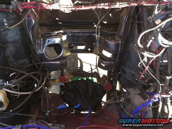 Engine bay with wiring and parts removed, showing frame and firewall