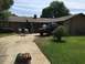 1989 Ford Bronco - A black pickup truck is parked in the driveway of a house, with people playing a yard game.