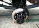 1989 Ford Bronco - Close-up of a vehicle's rear brake assembly, a black caliper and hub, with leaf springs visible overhead.
