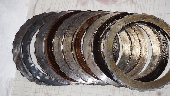 Stack of used transmission clutch plates with visible wear and oil residue
