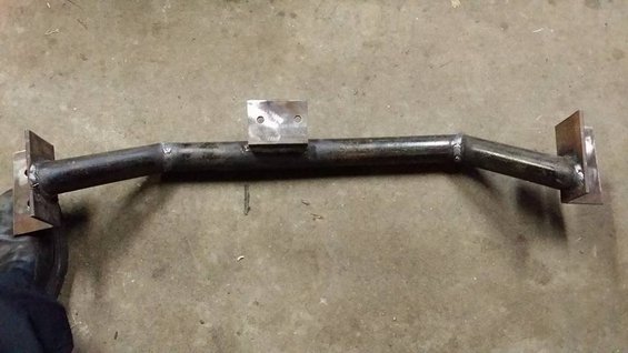 Metal crossbar with welded mounting plates on concrete floor