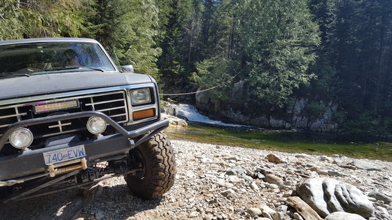 Gray SUV with off-road lights and winch parked by a waterfall