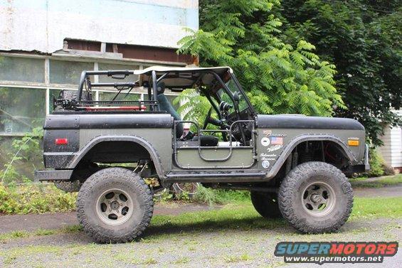 Side view of a 1972 Ford Bronco with off-road tires and a roll cage