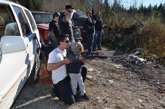 White SUV and red Jeep parked on dirt road with people holding rifles