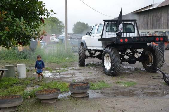 Rear view of white pickup truck with oversized tires and pirate flag
