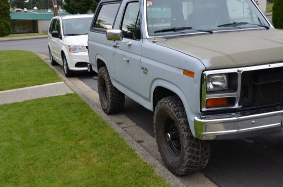 Gray Ford Bronco parked on street next to white minivan