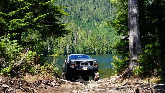 Ford F-Series truck parked by a lake with trees in background