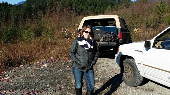 Woman in jeans and jacket stands between a white Jeep Grand Cherokee and a dark Ford Bronco with its tailgate open