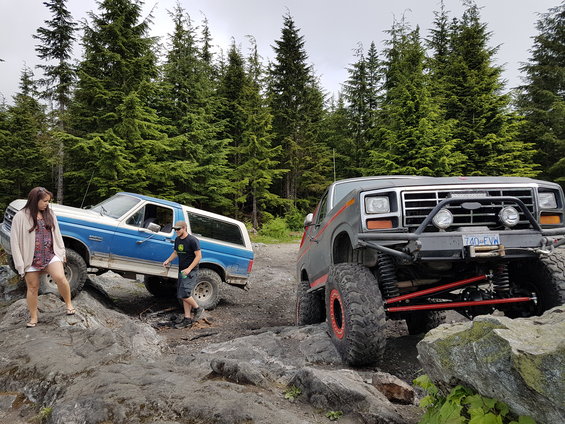 Gray Ford Bronco with off-road modifications and a blue Ford Bronco on rocks