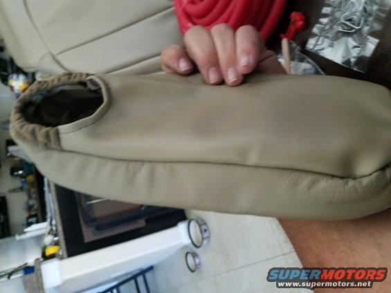 tan car seat armrest cover with patterned lining, held by a hand