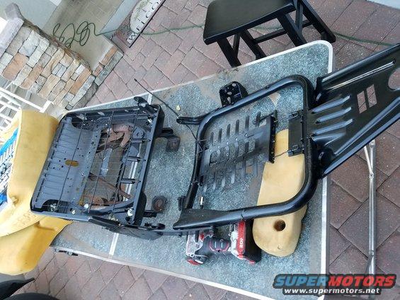 Disassembled vehicle seats with yellow foam and black metal frames on a table