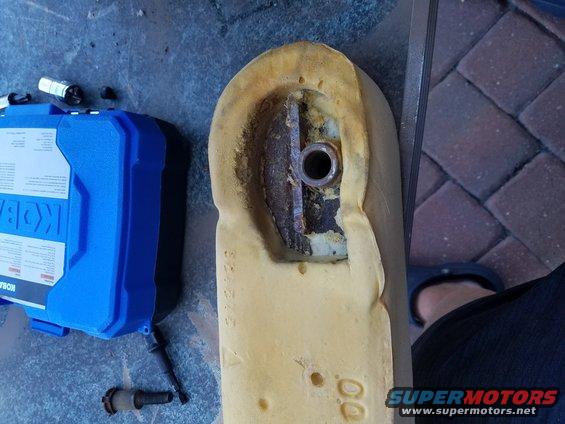Car seat foam with exposed metal bracket and bolt hole, next to a blue toolbox