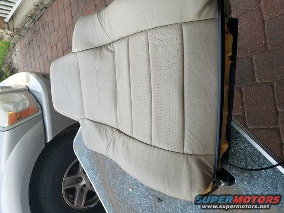 tan leather car seat with perforated inserts, part of a silver car visible