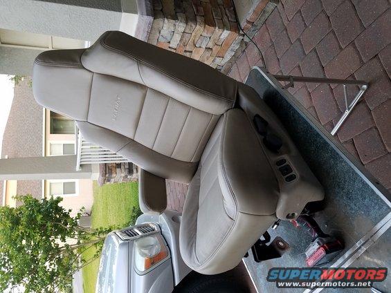 Tan leather car seat with power controls on the side, resting on a metal table