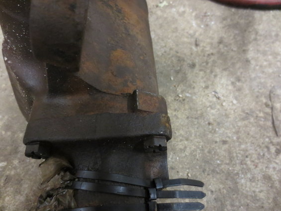 Close-up of a rusted metal component secured with bolts and black zip ties