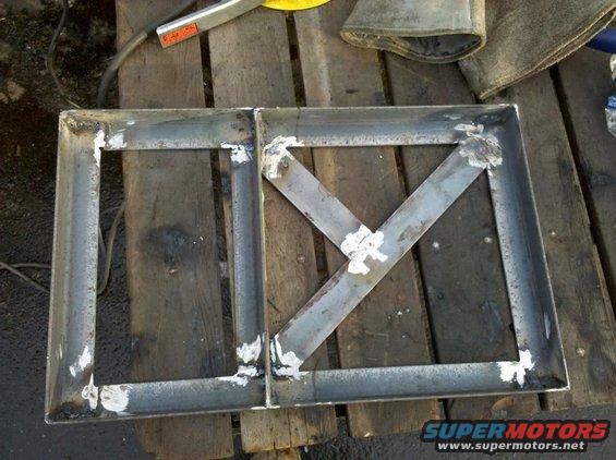 Welded metal frame with X bracing on a wooden surface