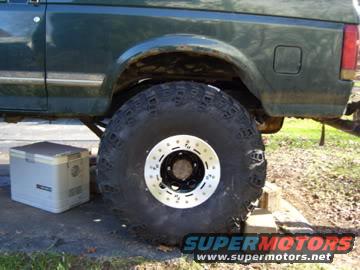 Green Ford Bronco rear wheel and fender well, with a white cooler beside it