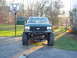 1989 Ford Bronco - Front view of a lifted 1989 Ford Bronco with large tires, parked in a driveway.
