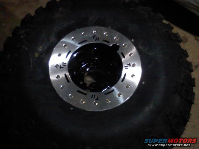 Tire with a silver wheel and black hub, showing bolt holes and 'TR' markings