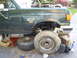 1989 Ford Bronco - Green SUV with hood open and front wheel removed, supported by jack stands.