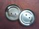 1989 Ford Bronco - Two metal hubcaps, each with two circular holes, are shown against a red fabric background.