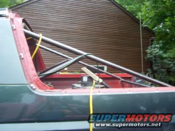 Roll cage structure inside a vehicle, with yellow straps and a SuperMotors logo
