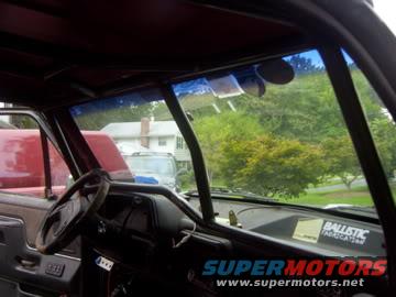 Interior view of a vehicle with a prominent roll cage and a 'BALLISTIC' sticker