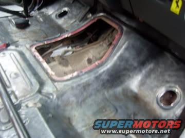 Bare metal interior floor with cut-out and red trim, tool visible