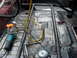 1989 Ford Bronco - Roll cage installation in progress inside a vehicle, with tools and an angle grinder present.