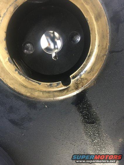 Close-up of a fuel pump assembly with a central opening and two visible screws